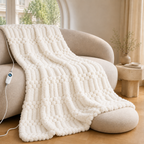 Milk white textured heated throw blanket on a neutral sofa with its controller.